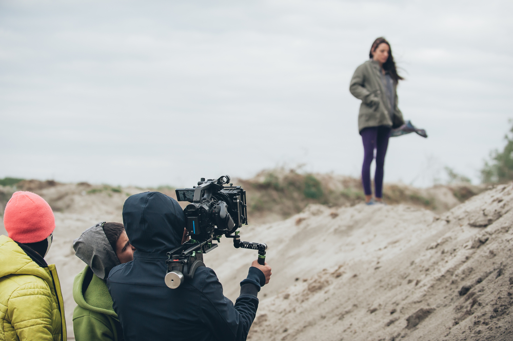 Woman,Holding,Microphone,On,A,Boom,During,Video,Production,Capturing Actress in front of the camera crew on local film set
